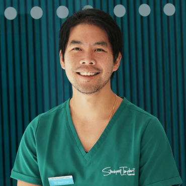 Dr Jason Fan, smiling, in green clinical scrubs.